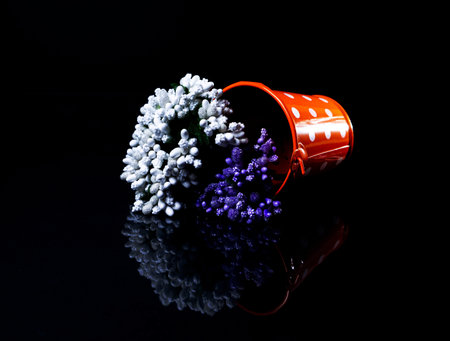 aluminum ice bucket laid in wait for use. stainless multi-colored buckets with reflection, black background isolated, with green blue flowersの写真素材