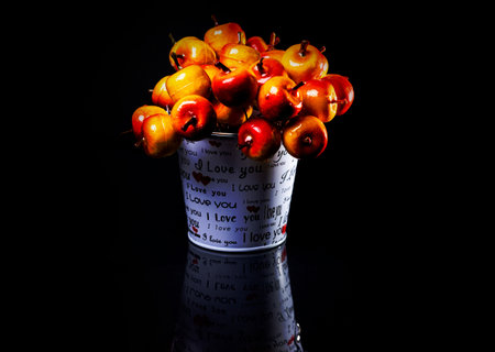 aluminum ice bucket laid in wait for use. stainless multi-colored buckets with reflection, black background isolated, with red applesの写真素材