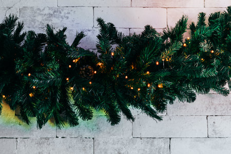 Christmas fir tree with lights on white brick background with copy spaceの写真素材