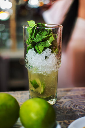 Bartender making refreshing coctail on a bar background. Dark moody style. Ice in tha glass Shakingの写真素材