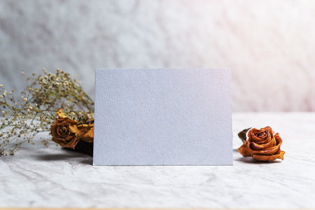 Blank card and wilted flowers on marble background. Concept of nostalgia, breakup, disappointment, separation.の写真素材