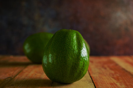 Avocados on wooden table. Isolated avocados in foreground.の写真素材