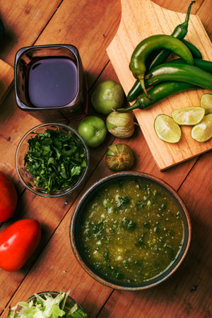 Bowl with green sauce and vegetables on a wooden table. Typical Mexican food.の写真素材