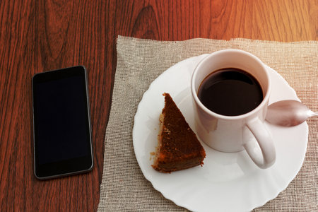 Cup of coffee and cell phone on wooden table.の写真素材