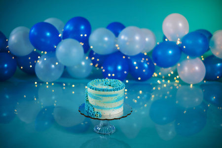 Blue and white birthday cake with balloons in the background. Photo set decoration for photo shoot.