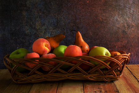 Fruits in wicker basket on wooden table.の写真素材