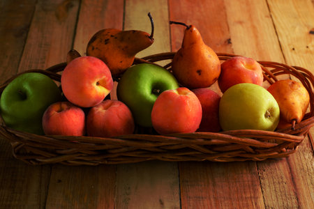 Fruits in wicker basket on wooden table.の写真素材