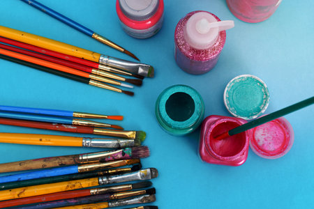 Group of used brushes and paint pots on blue background.の写真素材