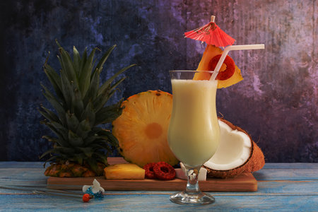 Pina colada, tropical cocktail. Glass of pina colada on a blue wooden table with the components of the cocktail in the background.の写真素材