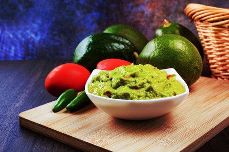 Guacamole served on a white plate on a wooden table. Guacamole ingredients.の写真素材