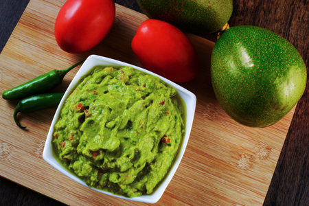 Guacamole served on a white plate on a wooden table. Guacamole ingredients.の写真素材