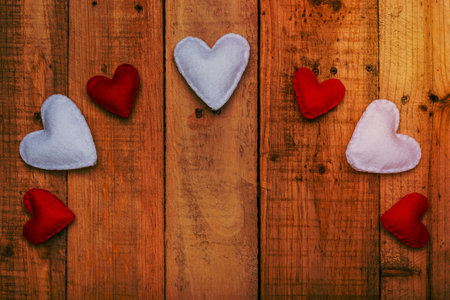 Group of hearts made of felt on wooden table forming an arch. Valentine's day background.の写真素材