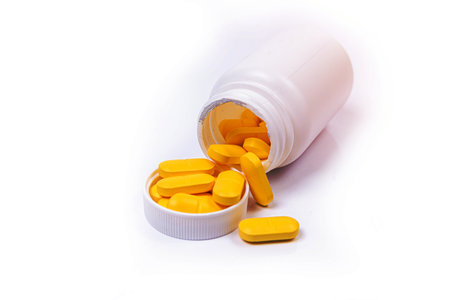 Medical white black orange pills spill out of a white jar on an isolated on white backgroundの写真素材