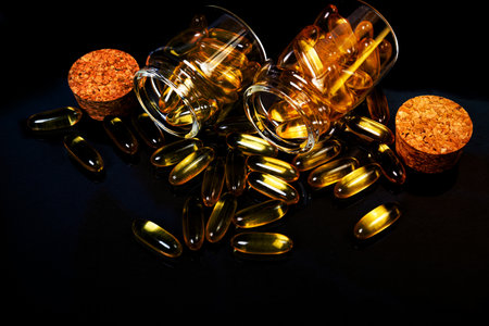 Fish oil capsules. Yellow omega 3 pills in jar on the dark black. fish oil capsules in wineglass glass . in jar. in bucket ampoules. Isolated on blackの写真素材