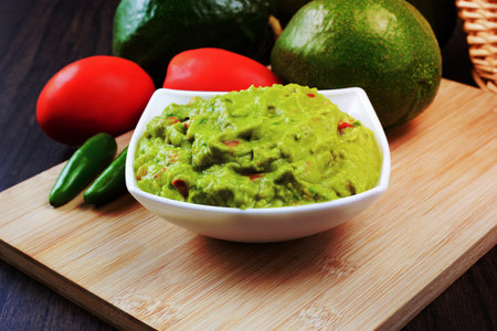 Guacamole served on a white plate on a wooden table. Guacamole ingredients.の写真素材