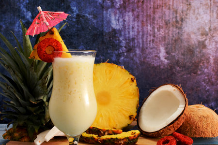 Pina colada, tropical cocktail. Glass of pina colada on a blue wooden table with the components of the cocktail in the background.の写真素材