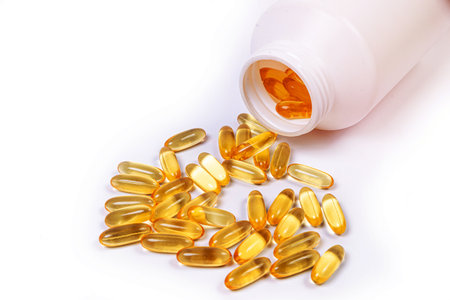 Medical white black orange pills spill out of a white jar on an isolated on white backgroundの写真素材