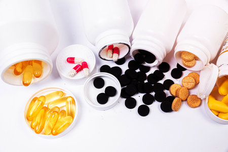 Medical white black orange pills spill out of a white jar on an isolated on white backgroundの写真素材
