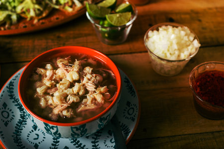 Pozole served in a deep dish, with salsa and vegetables on a wooden table. Typical Mexican food.の写真素材