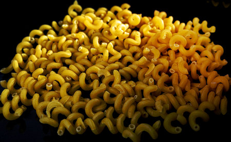 raw pasta in glass jar, wine glass. in bucket. raw pasta on black background. front view raw pasta, dropped from hand, place for text, yellow long spaghetti straws, food ingredientsの写真素材