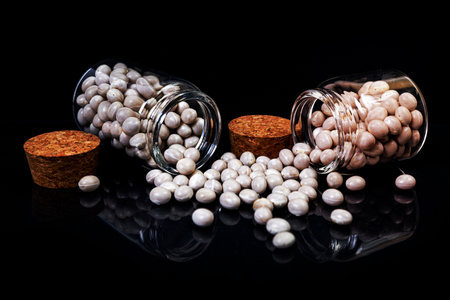 raw white beans in glass jar, wine glass. in bucket. raw white beans on black background. front view raw white beans, dropped from hand, isolated on blackの写真素材