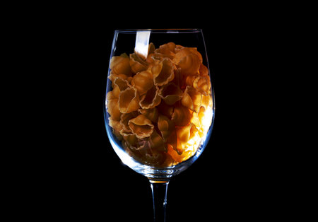 raw pasta in glass jar, wine glass. in bucket. raw pasta on black background. front view raw pasta, dropped from hand, place for text, yellow long spaghetti straws, food ingredientsの写真素材