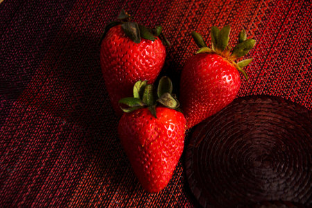 Strawberries on red textured tablecloth. Strawberries in foreground.の写真素材