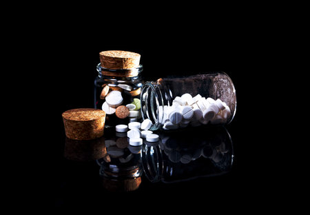 white orange pills in wineglass glass . in jar. in bucket Isolated on black set of capsule and pills inside wineglass closeup, selective focus, side viewの写真素材