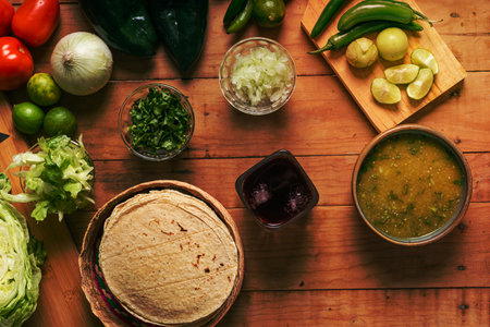 Tortillas, bowl with green sauce and vegetables on a wooden table. Typical Mexican food.の写真素材