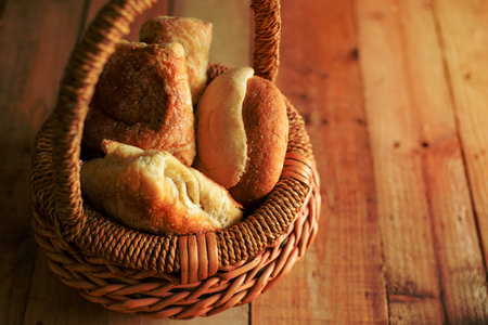 Wicker basket with sweet breads on wooden table. Blue background.の写真素材