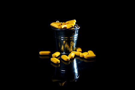 white orange pills in wineglass glass . in jar. in bucket Isolated on black set of capsule and pills inside wineglass closeup, selective focus, side viewの写真素材
