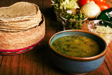 Tortillas, bowl with green sauce and vegetables on a wooden table. Typical Mexican food.の写真素材