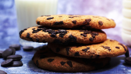 American chocolate chip cookies stacked on top of each other with milk in a glass on a gray background. Traditional rounded crunchy dough with chocolate chips. Bakery. Delicious dessert, pastriesの写真素材