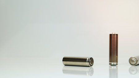 AA alkaline rechargeable batteries on white glossy background with reflection. Close up three empty batteries with copy spaceの写真素材