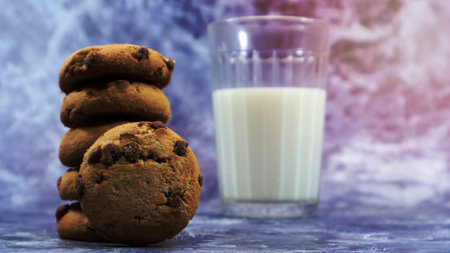 American chocolate chip cookies stacked on top of each other with milk in a glass on a gray background. Traditional rounded crunchy dough with chocolate chips. Bakery. Delicious dessert, pastriesの写真素材