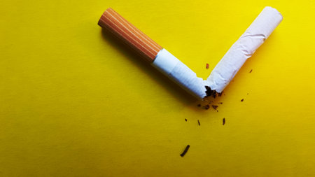 Broken cigarette isolated on a yellow background. View from above.の写真素材