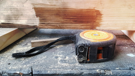 Instrument measuring tape under a layer of dust on a table in a workshop.の写真素材