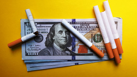 Classic cigarettes stand on one hundred US dollar bills. Cigarettes on a hundred dollar bill on a yellow background.の写真素材