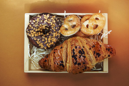 Fresh chocolate donut, croissant and cookies isolated on delicate coffee or brown background. Delicious desserts. Sweet food concept for your design and print. Top view, flat lay. Copy spaceの写真素材