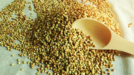 Buckwheat scattered background, raw green cereal in a wooden spoon. Healthy groats. Organic raw non-fried vegetarian food. The concept of a healthy and balanced diet. Diet product. healthy groatsの写真素材