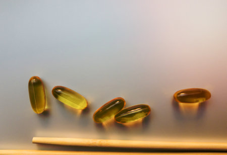 Fish oil capsules with Chinese chopsticks. Omega 3 on a white background. High Resolution Product. Food supplement. Vitamins for a healthy lifestyle. Fatty acid. Metabolism in the bodyの写真素材