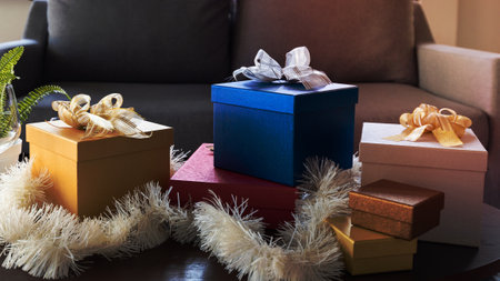 Beautiful Christmas gift boxes wrapped in colourful paper with ribbon bow on table in living room at homeの写真素材