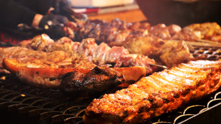 Fried pork ribs. Grilled pork kebabs on a teapot. Barbecue Kid on the grill. grilled kebab, kebab. Festival of delicious fried street food. The meat on the bone, the cooking process.の写真素材