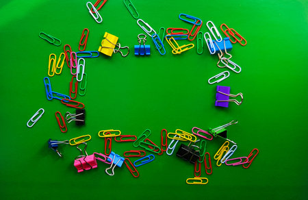 pile of paper clips isolated on green background, documents, office supplies concept, dirty office desk. Empty place for writing and text. Top view, layout. flat lay.の写真素材