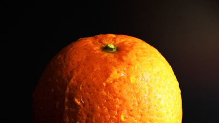 Static non-moving wet and wet whole orange with drops of water on a bright orange peel, on a black background. fruits for diet and healthy eating. Citrus fruits, side rain, tropical fruits close-up.の写真素材