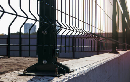 Steel lattice green fence with wire. Fencing. Grid industrial wire fence panels, pvc metal. Installation of sectional fencing. Welded mesh fence. Installation of a grid for fencing the territoryの写真素材