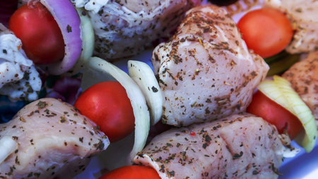 Raw pork shashlik with spices, cherry tomatoes and onions on skewers ready to cook. Fresh raw kebabの写真素材