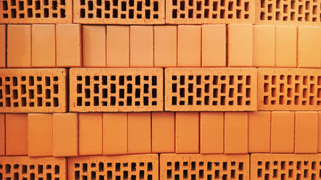 Red brick background with holes. Red perforated brick with rectangular holes. Rough texture of rows of red light bricks. View of the corrugated side and perforated upper surfaces of the clay brickの写真素材