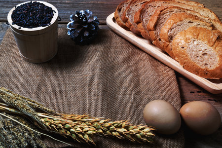 bread loaf and wheat ears and sack on wooden background.の写真素材