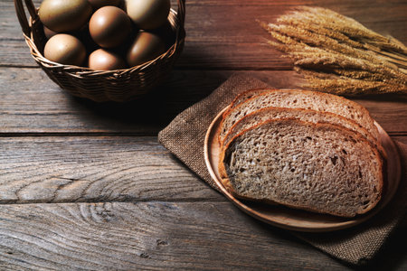bread loaf and wheat ears and sack on wooden background.の写真素材